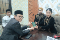 Kepala KUA Kecamatan Kota Sumenep, Marwan menyerahkan buku nikah usai akad (Foto: Istimewa)